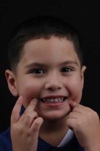 Photo of child smiling and showing teeth with fingers